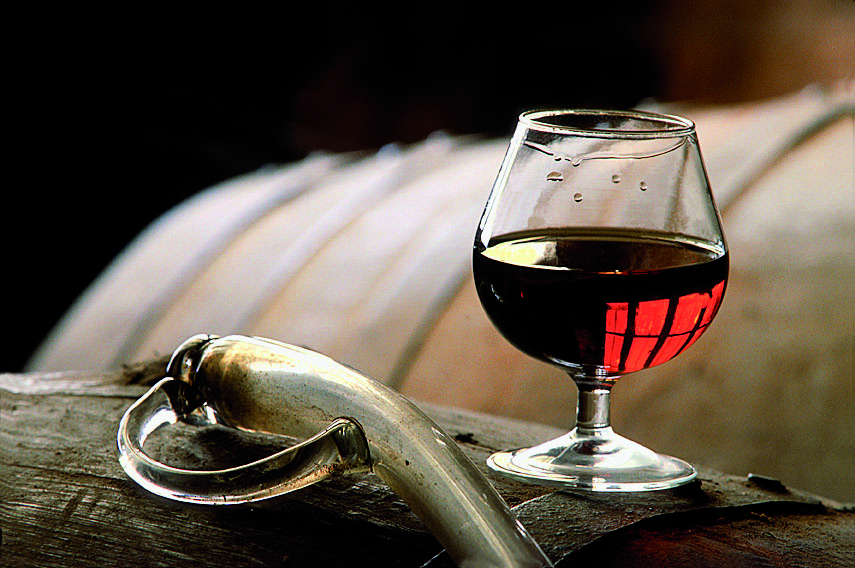 Pipette en verre et verre d'armagnac sur des barriques,dans les chais des Ets Delord à Lannepax dans le Gers.